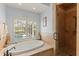 Beautiful bathroom featuring a tub, natural stone, glass enclosed shower, and backyard views at 4871 Hoyer Dr, Sarasota, FL 34241
