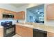 Kitchen featuring oak cabinets, black appliances, and a passthrough to the living area at 5015 98Th E Ave, Parrish, FL 34219