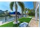 Landscaped backyard featuring artificial turf, palm trees, cornhole game, and private boat lift at 511 Loquat Dr, Anna Maria, FL 34216