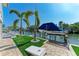 Spacious backyard with artificial turf, palm trees, cornhole game, and private boat lift at 511 Loquat Dr, Anna Maria, FL 34216