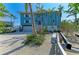A waterfront home showcasing a garage, staircase, lush tropical landscaping, and a canal nearby at 511 Loquat Dr, Anna Maria, FL 34216