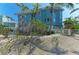 A waterfront home showcasing a garage, elevated construction, lush tropical landscaping, and a canal nearby at 511 Loquat Dr, Anna Maria, FL 34216