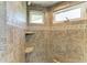 Shower features stone-look tile, built-in shelving, and dual windows for natural light at 511 Loquat Dr, Anna Maria, FL 34216