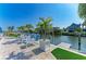 Waterfront patio with comfortable lounge chairs, lush palm trees, and private dock access at 511 Loquat Dr, Anna Maria, FL 34216