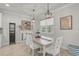 Bright dining area featuring a light-wood table with white chairs, pendant lighting, and a window with natural light at 5750 Long Shore Loop, Sarasota, FL 34238