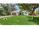 Charming single-story home with a well-manicured lawn, modern wood garage door, and lush tropical landscaping at 6136 Hollywood Blvd, Sarasota, FL 34231