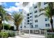White modern condo building featuring tropical landscaping with palms, and secure gated entrance at 650 Golden Gate Pt # 602, Sarasota, FL 34236