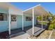 Cozy covered front porch features light blue siding, white trim, a decorative wreath, and a gray deck at 6520 Clemson St, Bradenton, FL 34207