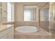 Well-lit bathroom featuring a soaking tub under a glass block window, next to a shower enclosure at 708 Foggy Morn Ln, Bradenton, FL 34212