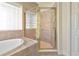 Bathroom with a tiled shower enclosure, large tub, and glass block window for natural light at 708 Foggy Morn Ln, Bradenton, FL 34212