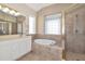 Bright bathroom featuring a soaking tub, glass block window, and tiled shower with gold trim at 708 Foggy Morn Ln, Bradenton, FL 34212