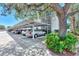 Covered parking featuring multiple cars, a mature tree, and landscaping at 7294 Cloister Dr # 7, Sarasota, FL 34231