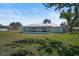 Back exterior view of the home showcasing a large yard, screened patio, and mature trees at 7523 S Leewynn Dr, Sarasota, FL 34240