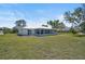 Rear exterior view featuring a large yard, covered patio, and well-maintained landscaping at 7523 S Leewynn Dr, Sarasota, FL 34240