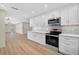 Well-lit kitchen featuring stainless steel appliances, white cabinets and light wood floors at 7523 S Leewynn Dr, Sarasota, FL 34240