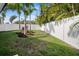 Spacious backyard with a white fence, green grass, and tropical landscaping at 7701 Palm Dr, Holmes Beach, FL 34217
