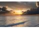 Stunning beach sunset with dramatic clouds, casting a golden glow over the ocean waters at 7701 Palm Dr, Holmes Beach, FL 34217
