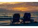 Beach scene featuring two chairs and a view of a sunset with colorful clouds at 7701 Palm Dr, Holmes Beach, FL 34217