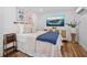 Well-lit bedroom features wood-look floors, woven cabinet, and beach artwork at 7701 Palm Dr, Holmes Beach, FL 34217