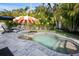 Inviting pool area with lush landscaping and a comfortable seating area under an umbrella at 7701 Palm Dr, Holmes Beach, FL 34217