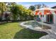 Beautiful backyard pool area surrounded by lush tropical plants and a patio area with umbrella at 7701 Palm Dr, Holmes Beach, FL 34217