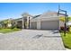 Beautiful home exterior featuring a paver driveway, three-car garage, and manicured landscaping at 8227 Nevis Run, Bradenton, FL 34202