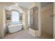 Bright bathroom with free-standing tub, arched window, and glass enclosed shower at 8328 Barton Farms Blvd, Sarasota, FL 34240