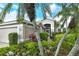 Beautiful home exterior with lush landscaping, including palm trees and colorful plants at 9411 Forest Hills Cir, Sarasota, FL 34238