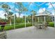 Spacious outdoor patio with seating, an umbrella for shade, and a view of the manicured backyard at 9411 Forest Hills Cir, Sarasota, FL 34238