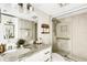 This bathroom features a walk-in shower, vanity with stone countertop and an updated mirror and light fixture at 988 Blvd Of The Arts # 1209, Sarasota, FL 34236