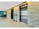 Hallway featuring elevators with a stone accent wall, creating a modern and stylish entrance to the building at 988 Blvd Of The Arts # 1209, Sarasota, FL 34236
