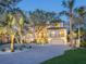 Elegant home with a paver driveway, lush landscaping, and a stately facade, illuminated at twilight at 1216 N Casey Key Rd, Osprey, FL 34229