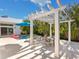 Beautiful outdoor patio featuring travertine floors, pergola, ceiling fan, outdoor dining, pool and lounge chairs at 144 Harrison Dr, Sarasota, FL 34236