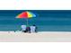 Seaside landscape with a colorful beach umbrella and beach chairs under the bright sunlight by the blue ocean at 1507 30Th W St, Bradenton, FL 34205