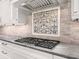 Close-up of a modern gas range with custom backsplash and granite countertops at 1575 Eastbrook Dr, Sarasota, FL 34231