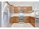 Modern kitchen featuring stainless steel appliances, granite countertops, stylish tile backsplash, and wooden cabinets at 17042 Hampton Falls Ter, Bradenton, FL 34202
