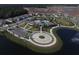 Aerial view of a luxurious community pool, clubhouse, and ample parking surrounded by lush landscaping and a serene pond at 177 Tierra Verde Way, Bradenton, FL 34212