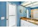 Updated bathroom features bright-blue walls, white vanity, white cabinets, and decorative mirror at 1878 Killdeer Ct, Venice, FL 34293