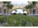 Elegant community entrance with lush landscaping, a grand archway, and palm trees at 20186 Benissimo Dr, Venice, FL 34293