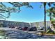 View of a parking lot in front of a light grey condo building with multiple palm trees and bright blue skies at 3108 Lake Bayshore Dr # 211, Bradenton, FL 34205