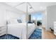 Bright bedroom with a four-poster bed and sliding glass doors that lead to a patio with water view at 340 Gulf Of Mexico Dr # 115, Longboat Key, FL 34228