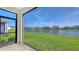 View from screened-in lanai of landscaped backyard and tranquil lake view at 427 157Th E Ct, Bradenton, FL 34212