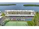Aerial view showcases the building, covered parking, and tennis courts, with a glimpse of the waterway at 4310 Falmouth Dr # 304, Longboat Key, FL 34228