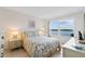 Bright bedroom boasts large window with water views, tile floors, white furniture, and a floral bedspread at 4310 Falmouth Dr # 304, Longboat Key, FL 34228