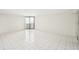 Bright empty living room with white tile flooring and glass sliding door to a balcony at 4822 Ocean Blvd # 11E, Sarasota, FL 34242