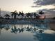 Beautiful outdoor pool reflects surrounding palms under a sky with colorful clouds at sunset at 5235 Cherry Hill Ave, Sarasota, FL 34234