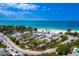 Aerial view of a busy beach with a parking lot, trees, and the ocean with a blue sky at 525 68Th St St, Holmes Beach, FL 34217