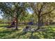 Community playground featuring modern play structures, picnic tables, and mature trees in a well-maintained grassy area at 5342 98Th E Ave, Parrish, FL 34219