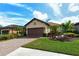 Charming home featuring a paver driveway and well-maintained landscaping, including palm trees, shrubs, and a lush green lawn at 5561 Sentiero Dr, Nokomis, FL 34275