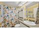 Bright bathroom with a vibrant, patterned shower curtain, vanity, and well-lit interior at 5614 Garden Lakes Dr, Bradenton, FL 34203